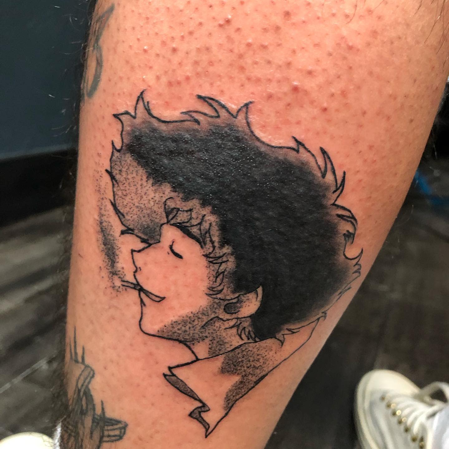 Minimalist tattoo of Spike Spiegel from Cowboy Bebop, smiling and smoking, with a textured shading effect